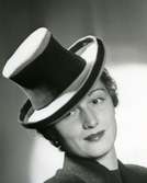 Porträtt av kvinna i hatt med brett hattband.