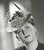 Porträtt av kvinna i hatt med flor och fjädrar.