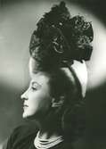 Porträtt av kvinna i hatt med dekorband och flor, av Monsieur Erik.