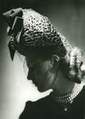 Porträtt av kvinna i hatt med dekorband och flor, samt treradigt pärlhalsband och chinjong, av Monsieur Erik.