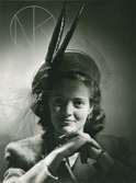 Porträtt av kvinna i hatt. Beige och brun filt med fasanpennor och flor. Hatt använd vid franska avdelningens uppvisning september 1947.