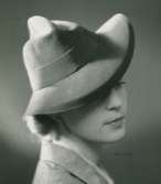 Fb, Porträtt av kvinna i hatt av Claude S:t Cyr. Lila filt.