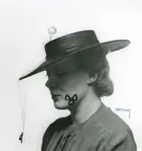 Fb, Porträtt av kvinna i hatt med flor och nål med kula.