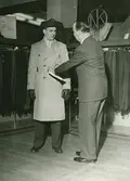 En man provar trenchcoat på Nordiska Kompaniets herrkonfektionsavdelning.