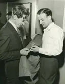 Två män tittar på en jacka med flagga på armen.