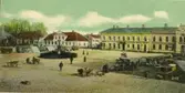 Varbergs torg med pågående torghandel. I bakgrunden kv Rådhuset och kv Apotekaren. Foto från början av 1900-talet.