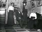 Familjeporträtt av Charlotte, August, Constance och Mina Bertilsson i inomhusmiljö.