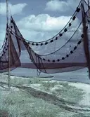 Ställning med fiskenät på tork, en båt ligger uppdragen på sandstranden