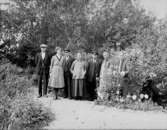 Grupp porträtterad i den grönskande trädgården på Rultane.
Från vänster: Artur, Naemi, Johannes, Anna (alla med efternamnet Pettersson), okänd, Augusta Forsberg och okänd.
Tillsammans med flox och astrar och framför meterhög gullboll lät sig gruppen fotograferas.
