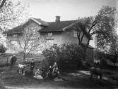 Mangårdsbyggnad med hästar och folk i trädgården