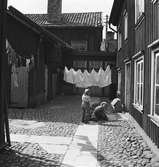 Gårdsinteriör med lekande barn och tvätt som hänger på tork, från Östra Holmgatan 6 i Jönköping på 1940-talet.