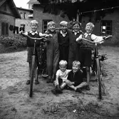 Sju pojkar med två cyklar utanför 
