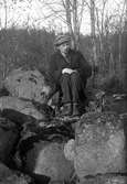 Gustav Andersson sitter bland stora stenar i skogen.