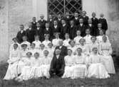 Konfirmandgrupp vid Simtuna kyrka, Uppland, sannolikt 23 juni 1911. I mitten kyrkoherde August Hylander (1852-1935).