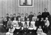 Gruppfoto av flickor och pojkar, samt fröken vid förhyrda skolan i Dvärred.