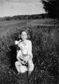 Inga-Lill Lipovsék 6 år, boende på Stretereds skolhem, troligtvis tillsammans med sin mamma på en sommaräng vid Stretereds skolhem, 1953. Ängen är där Sagåsens vårdavdelning byggdes.