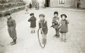 Bosgårdens barnträdgård 1939. Leif, Lille Göte, Göte med tunnband, Kicka och Mona leker utomhus.