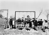 Bosgårdens barnträdgård 1938-1945. Fröken och barn som står vid en gungställning.