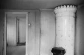 Roten M 9, årtal okänt. Omöblerat bostadsrum med kakelugn.