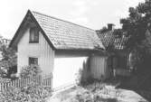 Exteriörbild av bostadshus med förstuga och uthus på Roten M 32 i Mölndals Kvarnby, 1972.