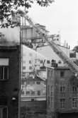 Soab-branden i Stora Götafors den 4 juni 1986. Brandmän bekämpar branden från Lilla Götafors samt med lyftkran.