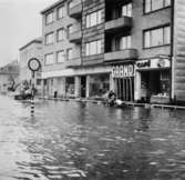 Cykelbud och hästtransport som färdas i vattenmassorna. Översvämning utanför Grand i Mölndalsbro kl 11.15 på förmiddagen. Omkring 1940.