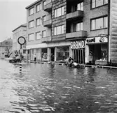 Cykelbud och hästtransport som färdas i vattenmassorna. Översvämning utanför Grand i Mölndalsbro kl 11.15 på förmiddagen. Omkring 1940.