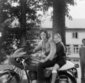 Inga-Lill Lipovsék sitter bak på en motorcykel, 1970- till 80-tal. Okänd förare. Hon bodde på Stretereds vårdhem från två års ålder till vuxen ålder.