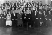 Mölndals körsällskap sittande respektive stående i en festlokal vid 20-årsjubileet 1955. Längst fram i mitten ses Gustav Svensson.