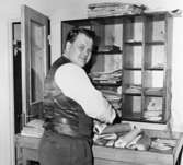 Lantbrevbärare Cyril Falk, postexpeditionen Lönsboda, försorterar post.
Foto, maj 1961.