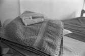 Dokumentation av Sagåsens flyktingförläggning 1992. Ett set med ren handduk, tandborste, tandkräm, kam och tvål som är placerade på en säng.