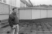 Dokumentation av Sagåsens flyktingförläggning 1992. En man står på en stenlagd plats, framför en byggnad. Insynsskydd syns i bakgrunden.
