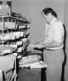 Överpostiljon Rolf Håkansson förbereder brevbäringsturen, på
postexpeditionen i Åkersberga.  Augusti 1961.