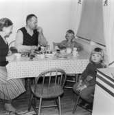 Trofina och Fedosja Jeutitonen äter kvällsmål i köket tillsammans med barnen Ulf och Marita Jerkeskog på Idunagatan 39, 1957.