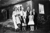 Familjerna Gustavsson och Svensson poserar utanför ladan på Långö på Solveigs dopdag 1949. Marianne Svensson står i mitten, Sonja Svensson bär Solveig.