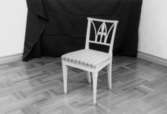 Vit, karmlös, klädd stol tillverkad av Nils Thorsson från Rösera i Lindome.