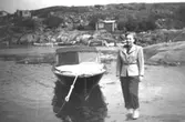 Kerstin Karlsson står vid en passbåt vid Smittens udde i Näset. 1950-tal. Kerstin är moster till givaren Alf Garthman.