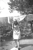 Givarens moster/fotografens syster, Ingrid Karlsson, hänger tvätt i Åbyområdet, 1955.