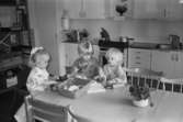 Tre små barn sitter vid köksbordet på Katrinebergs daghem. De 