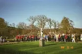 En folksamling som lyssnar på Frälsningsarméns blåsorkester, med en skulptur i förgrunden. Gunnebo slottspark, 1988.