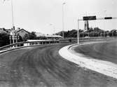 Man ser uppfartsvägen från Gamla Kungsbackavägen till Mölndals bro (Kvarnbygatsviadukten) under byggtiden 1975. I bakgrunden till vänster ses taket till Barnhemsgatan 16 (Ahlbergs skrädderi).