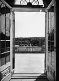 Vy mot altanen i söder, fotograferat inifrån Gunnebo slott genom två öppna fönster. 1958.