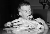 En pojke som sitter och äter. Holtermanska daghemmet 1953.