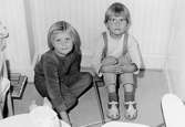 Två flickor som sitter på golvet framför ett element. Holtermanska daghemmet 1953.