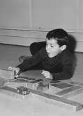 En pojke leker med träbyggklossar på golvet vid Holtermanska daghemmet 1953.