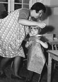 En lärarinna hjälper en flicka med förklädet vid Holtermanska daghemmet 1953..