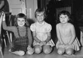 Tre flickor som sitter på golvet vid Holtermanska daghemmet 1953.