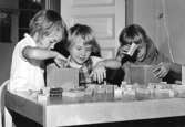 Tre flickor leker med byggklossar vid ett bord. Holtermanska daghemmet 1953.