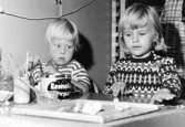 Två barn sitter vid ett bord och pysslar. Holtermanska daghemmet 1953.