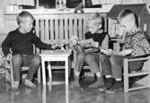 Tre pojkar sitter och läser vid ett barnmöblemang. Holtermanska daghemmet 1953.